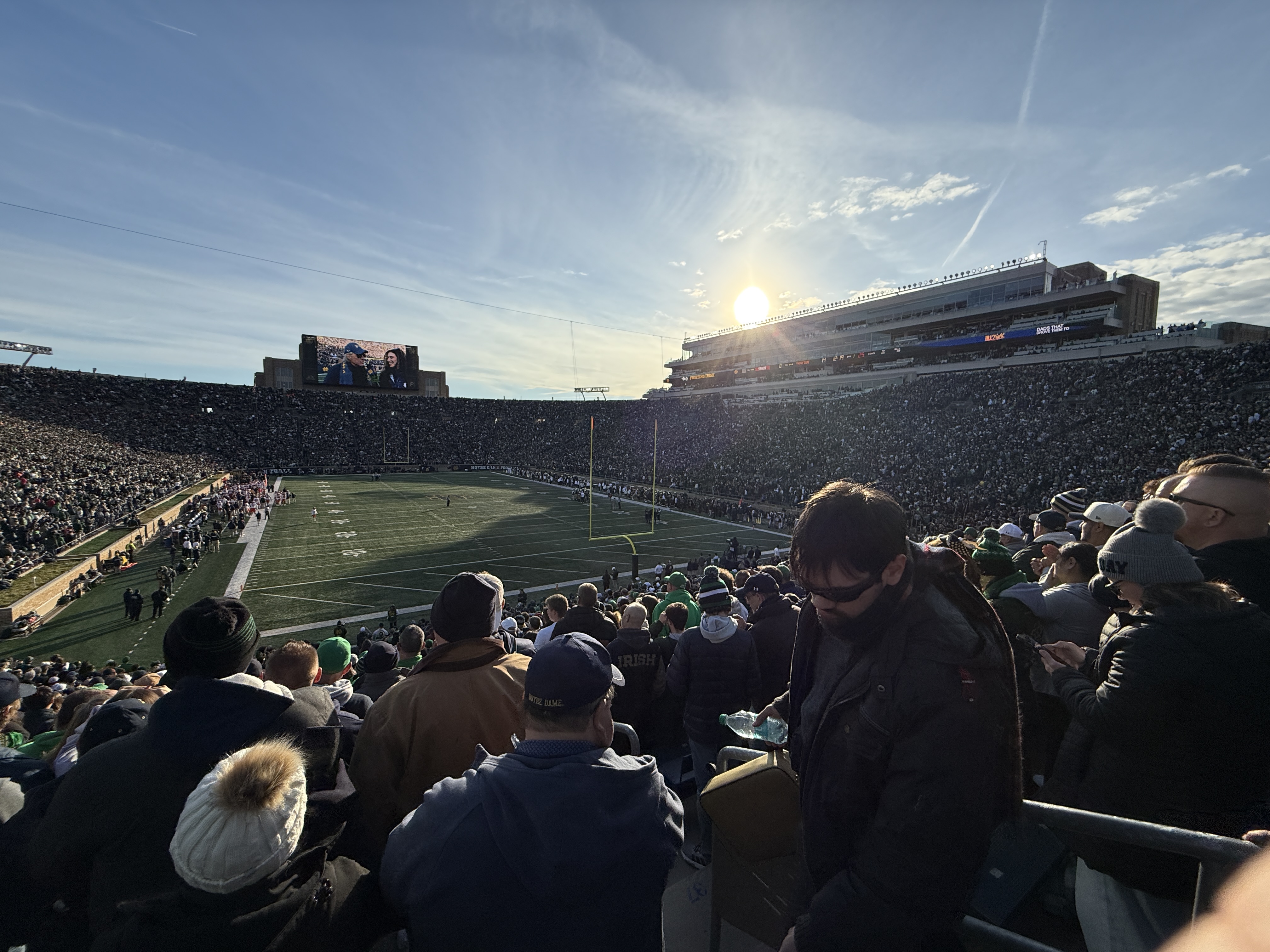 A packed football stadium in golden sunlight
