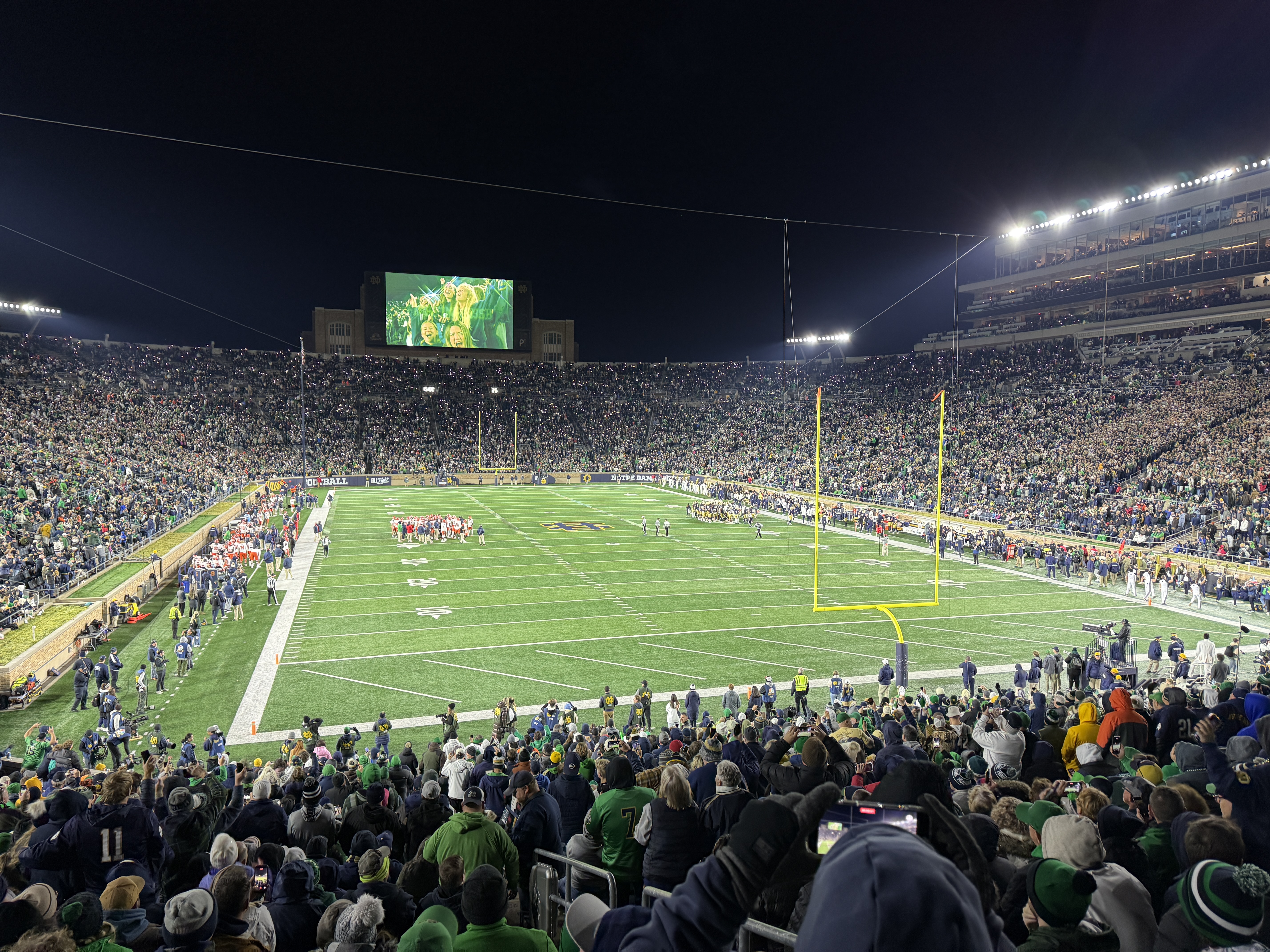 A packed football stadium under the lights