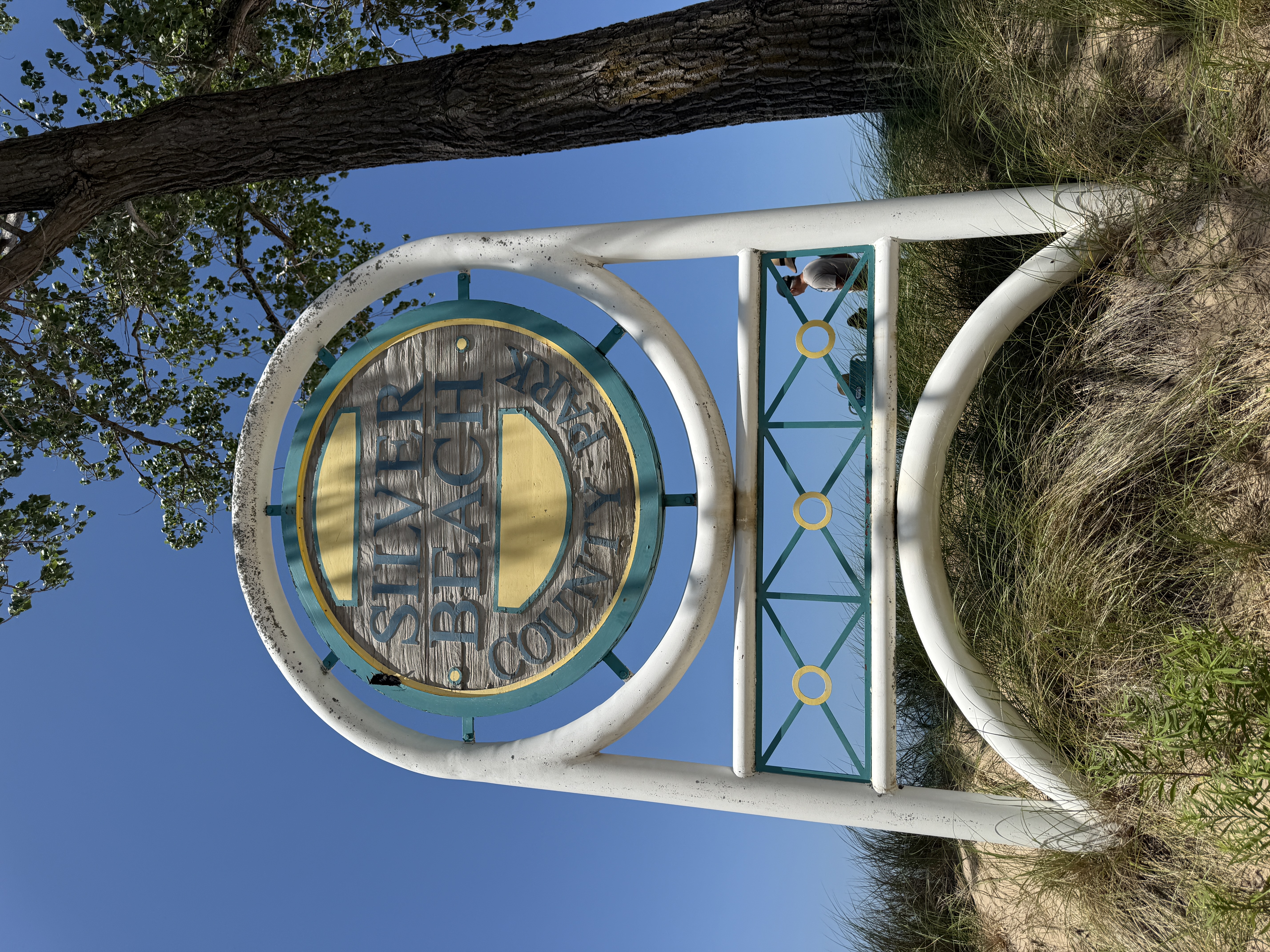 Silver Beach County Park sign framed by dune grass and a blue sky